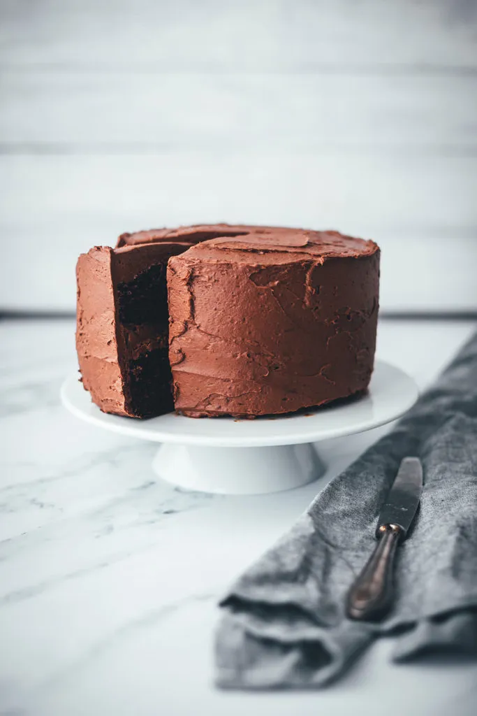 Ein Schokokuchen, liebevoll als Geburtstagstorte zubereitet, besticht durch seine dunkle Schokoladenfarbe und cremiges Frosting.