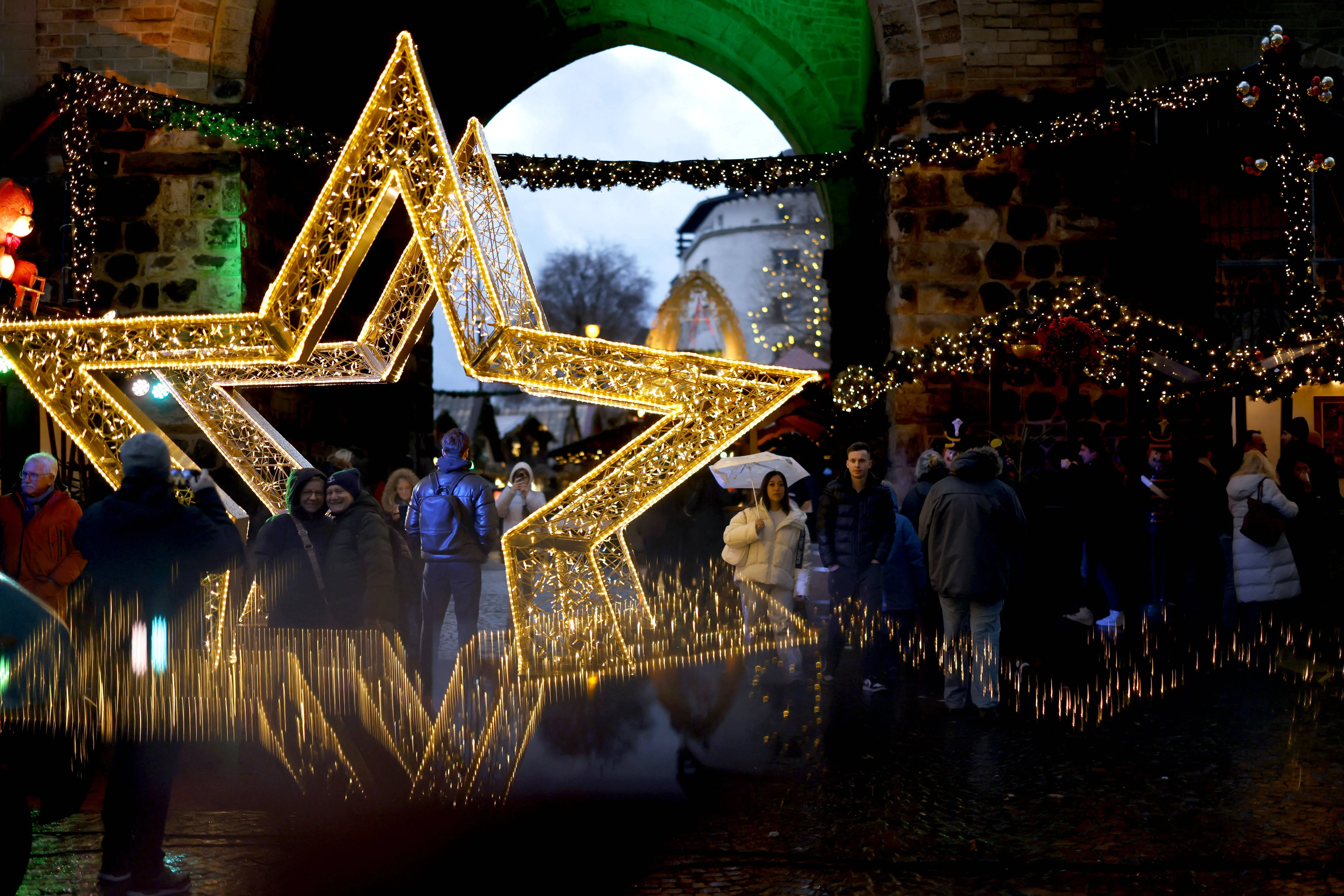 Ein stimmungsvoller Blick auf den Weihnachtsmarkt Essen-Steele bei Nacht, beleuchtet von warmen Lichtern und voller Leben
