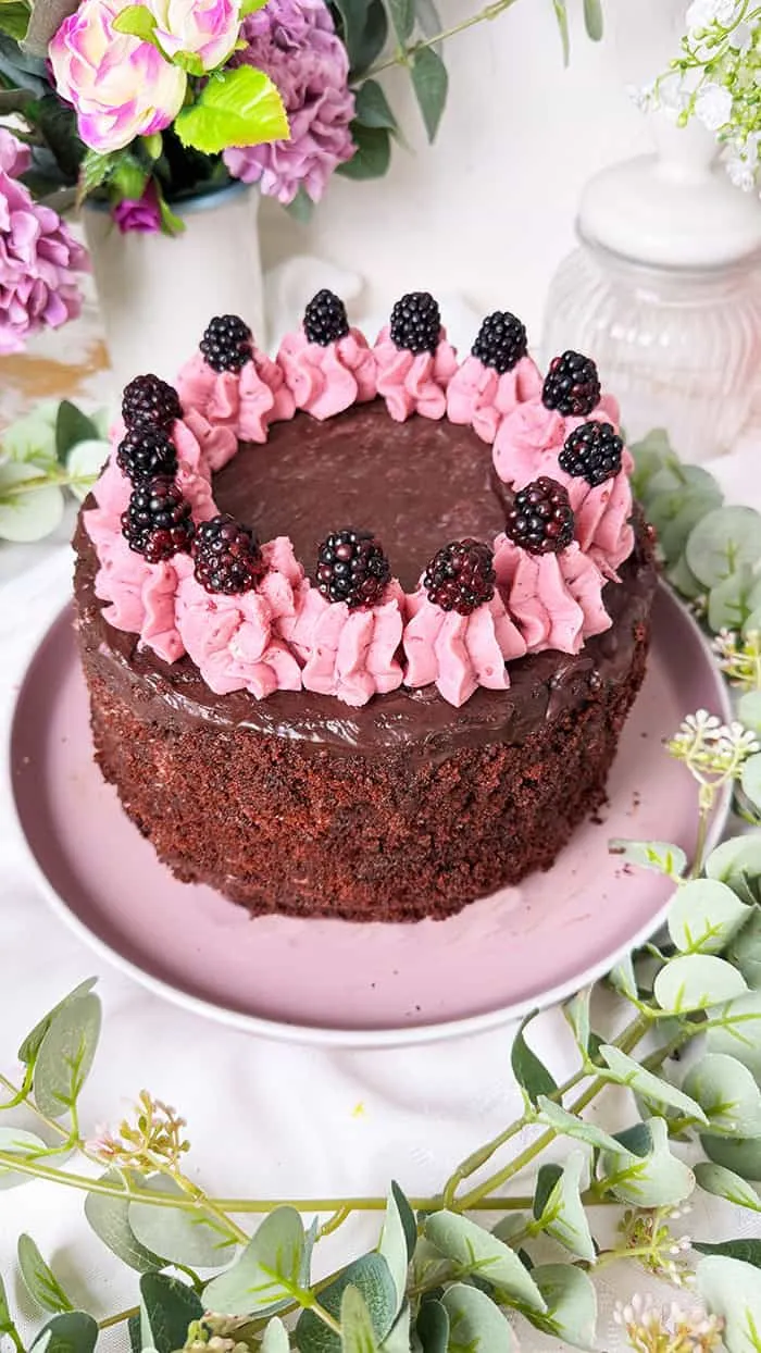 Ein Stück Brombeer Sahne Torte auf einem Teller, das Schichten aus Boden, Creme und Beeren zeigt