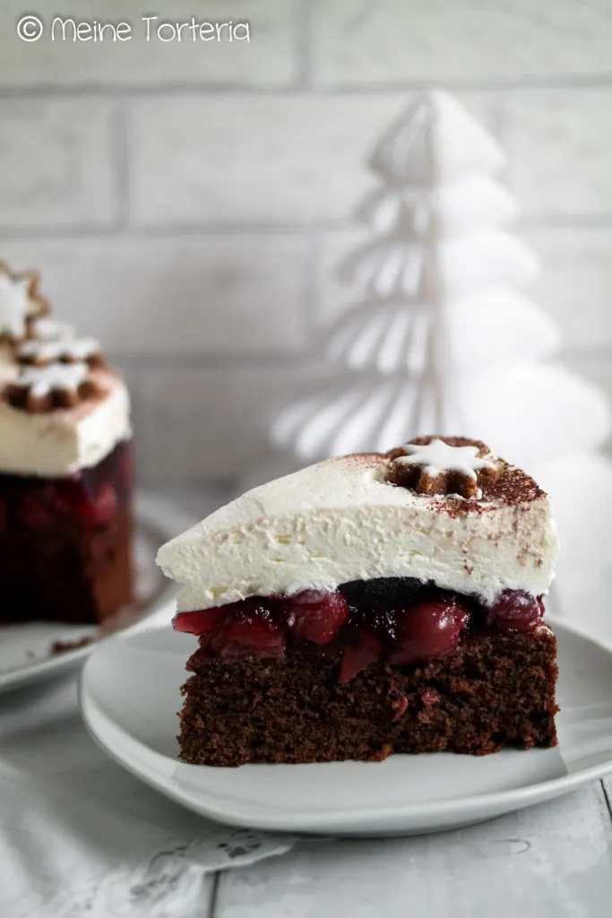 Ein Stück Glühwein Kirsch Torte auf einem Teller, mit Blick auf die saftigen Kirschen und die leichte Sahne.