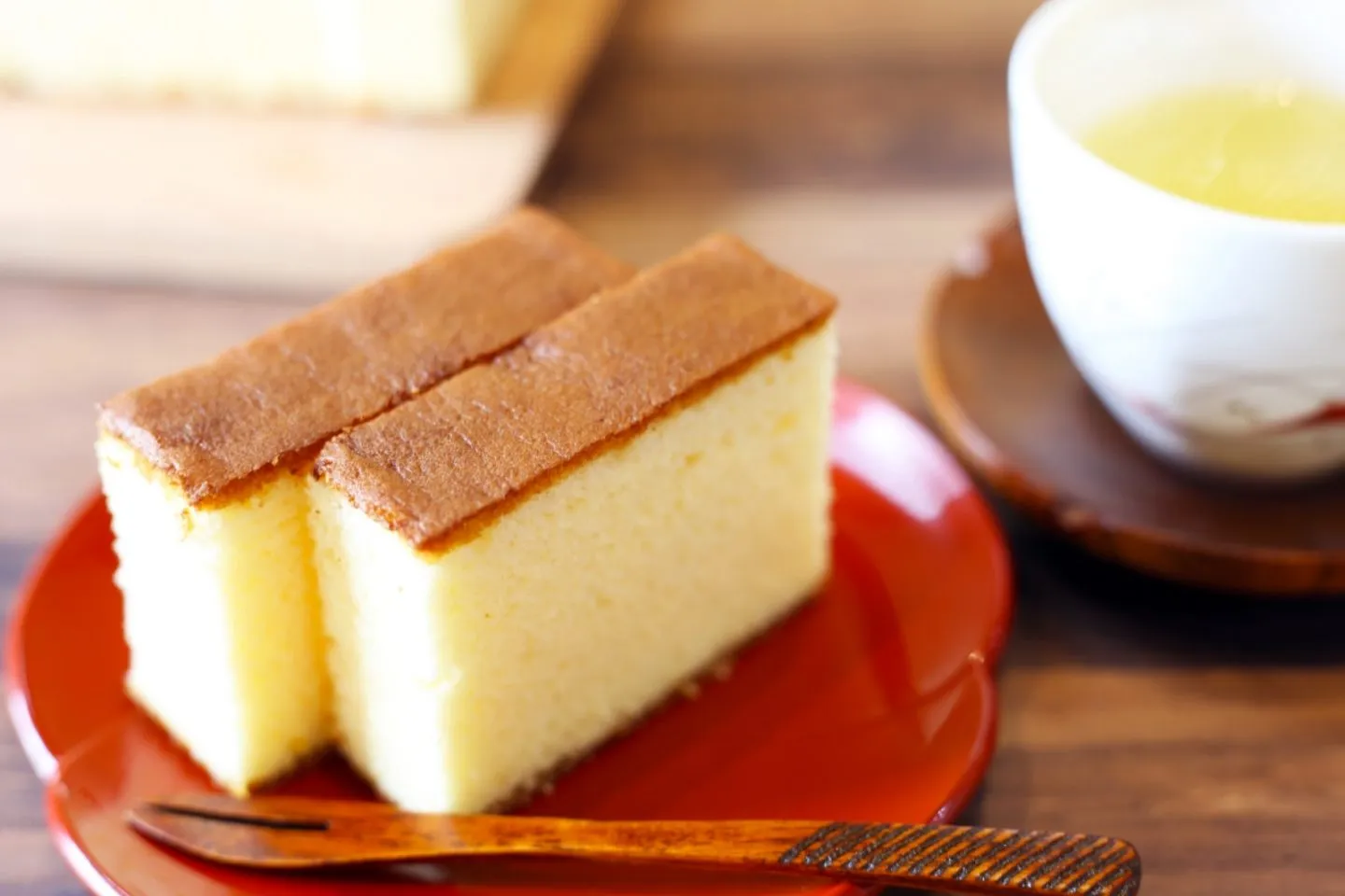 Ein Stück Kasutera mit goldener Kruste, serviert zu Kaffee, als Beispiel für japanischen Geburtstagskuchen