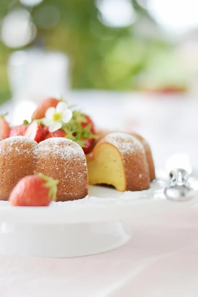 Ein Stück Kuchen mit wenig Zutaten, dekoriert mit frischen Erdbeeren und Blüten, ideal für ein schnelles Backerlebnis.