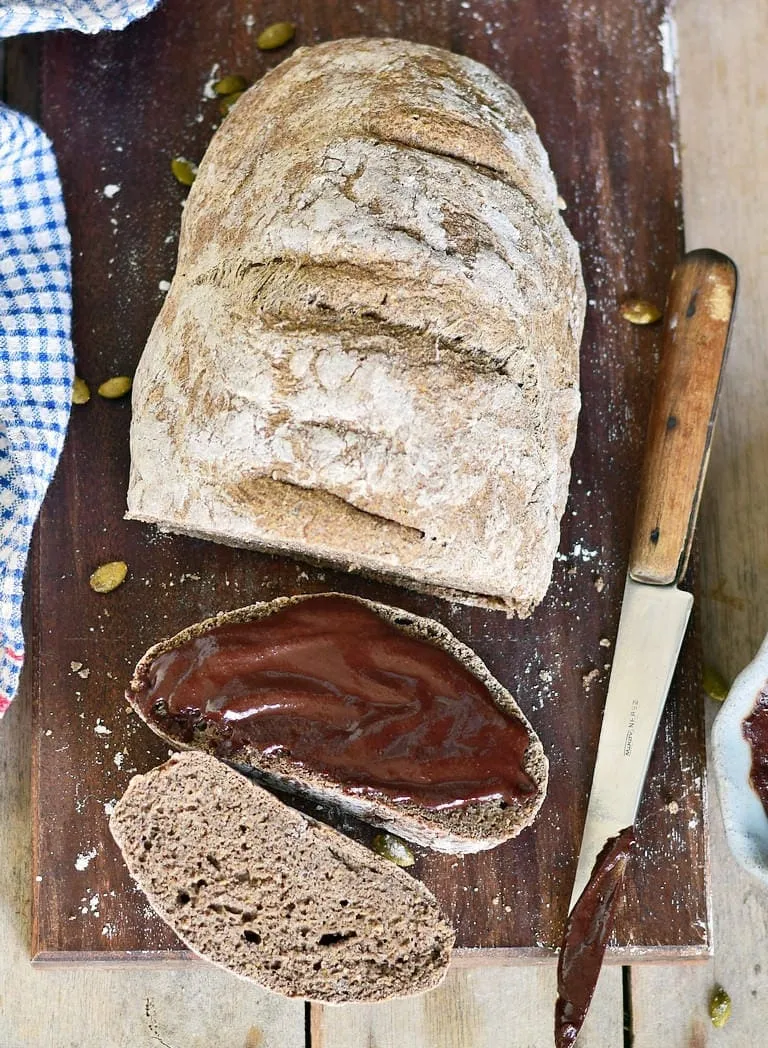 Ein Stück selbstgemachtes glutenfreies Brot, bestrichen mit einem cremigen veganen Schokoaufstrich