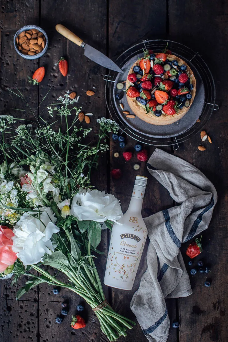 Ein Stück veganer Käsekuchen mit Beeren und einem Baileys Almande Getränk
