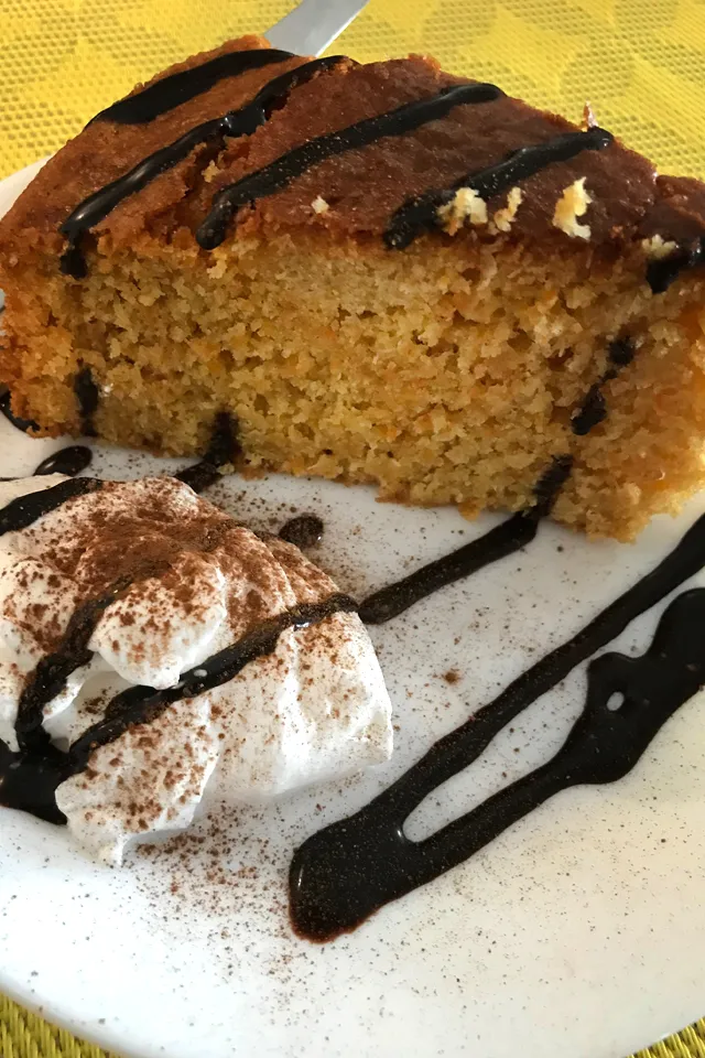 Ein Stück veganer Kuchen mit Sahne und Beeren, appetitlich auf einem Teller angerichtet