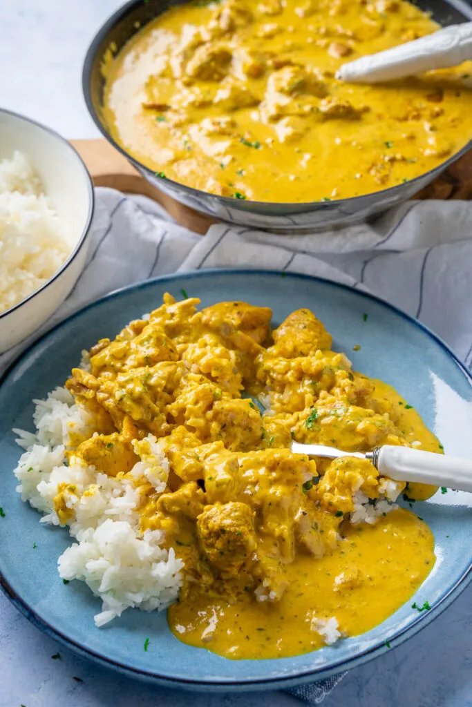 Ein Teller cremiges Hähnchen-Curry-Geschnetzeltes mit Reis, bereit zum Servieren
