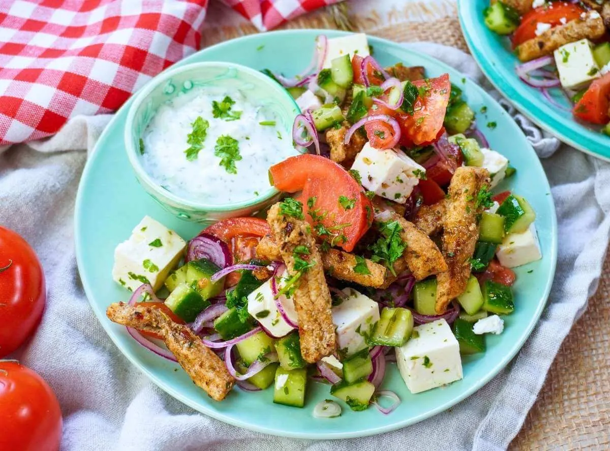 Ein Teller mit buntem Gyros-Salat, bestehend aus Fleisch, Gemüse und Dressing.