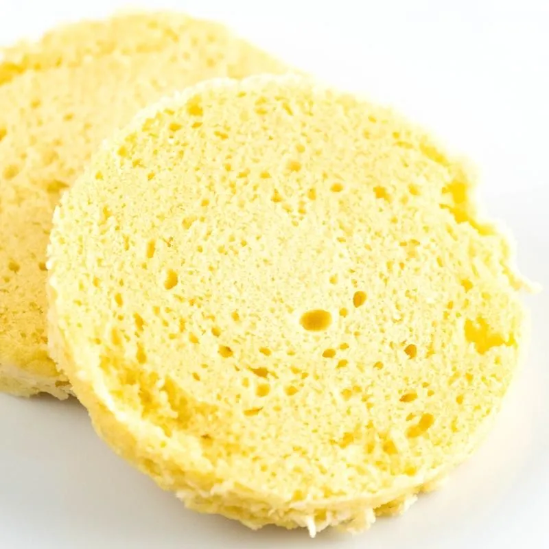 Ein Teller mit einem frisch zubereiteten Keto Mikrowellen-Brötchen, belegt mit Avocado, Ei und Bacon. Das Brötchen hat eine goldbraune Farbe und eine lockere Textur. Alt-Text: Keto Mikrowellen-Brötchen Rezept - Schnell und einfach zum ketogenen Frühstück