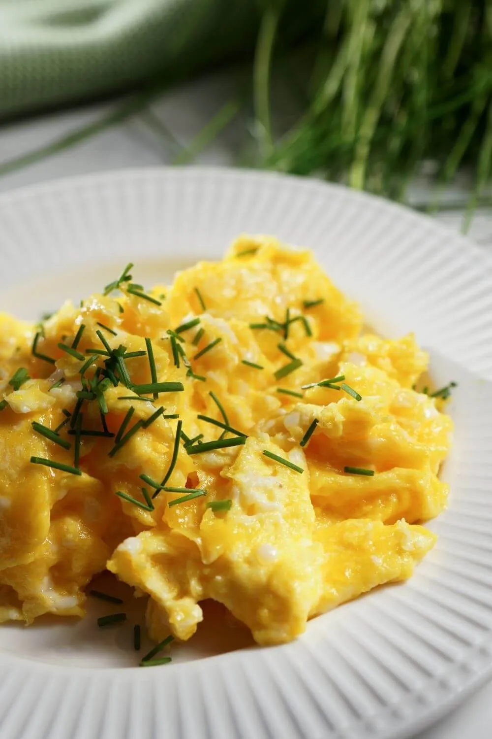 Ein Teller mit fluffigem Rührei, garniert mit frischen Kräutern.