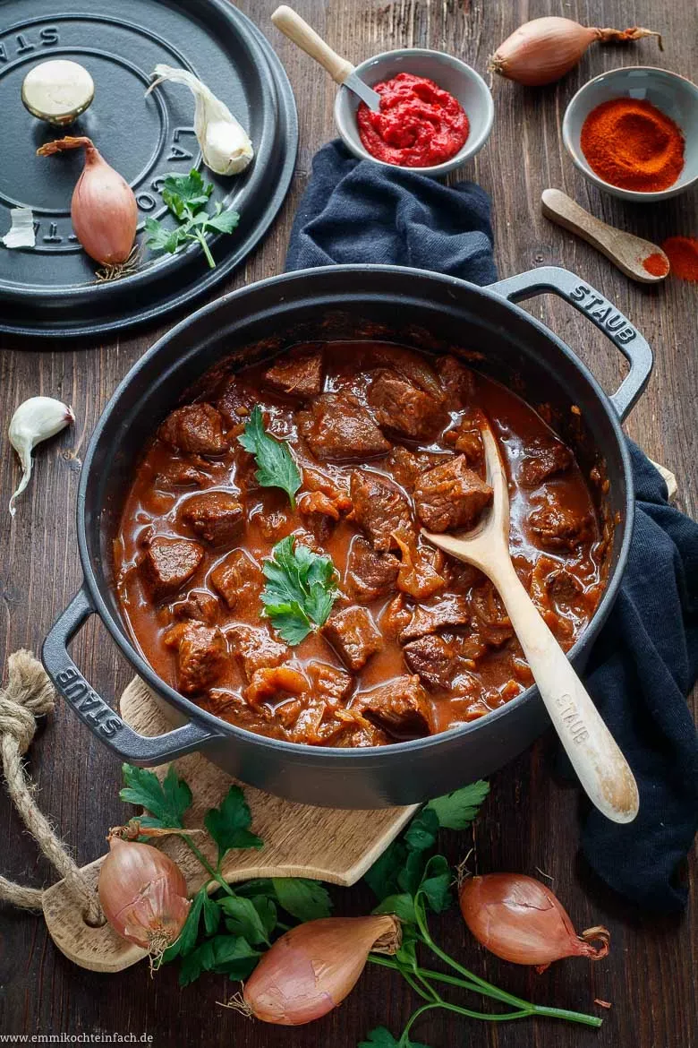 Ein Teller mit klassischem Rindergulasch, garniert mit frischer Petersilie, bereit zum Servieren, ein beliebtes deutsches Rezept.