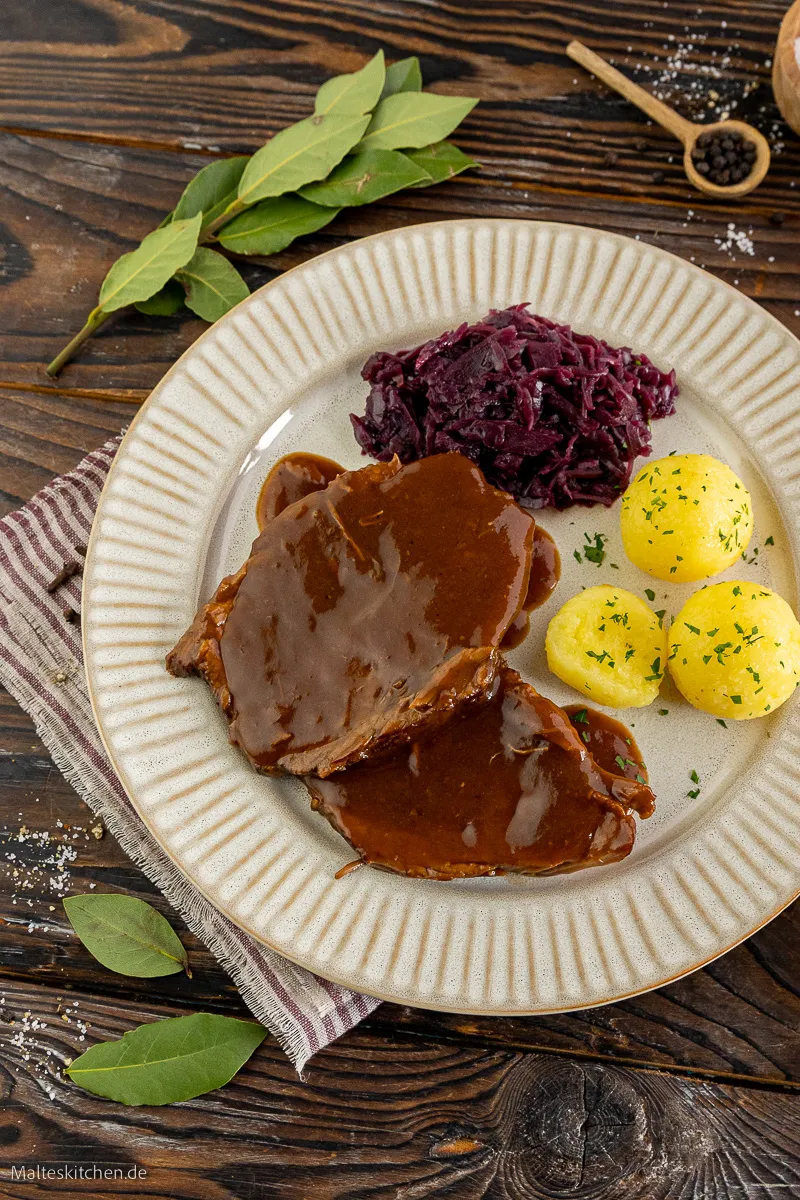 Ein Teller mit Rinderschmorbraten, Rotkohl und Klößen.
