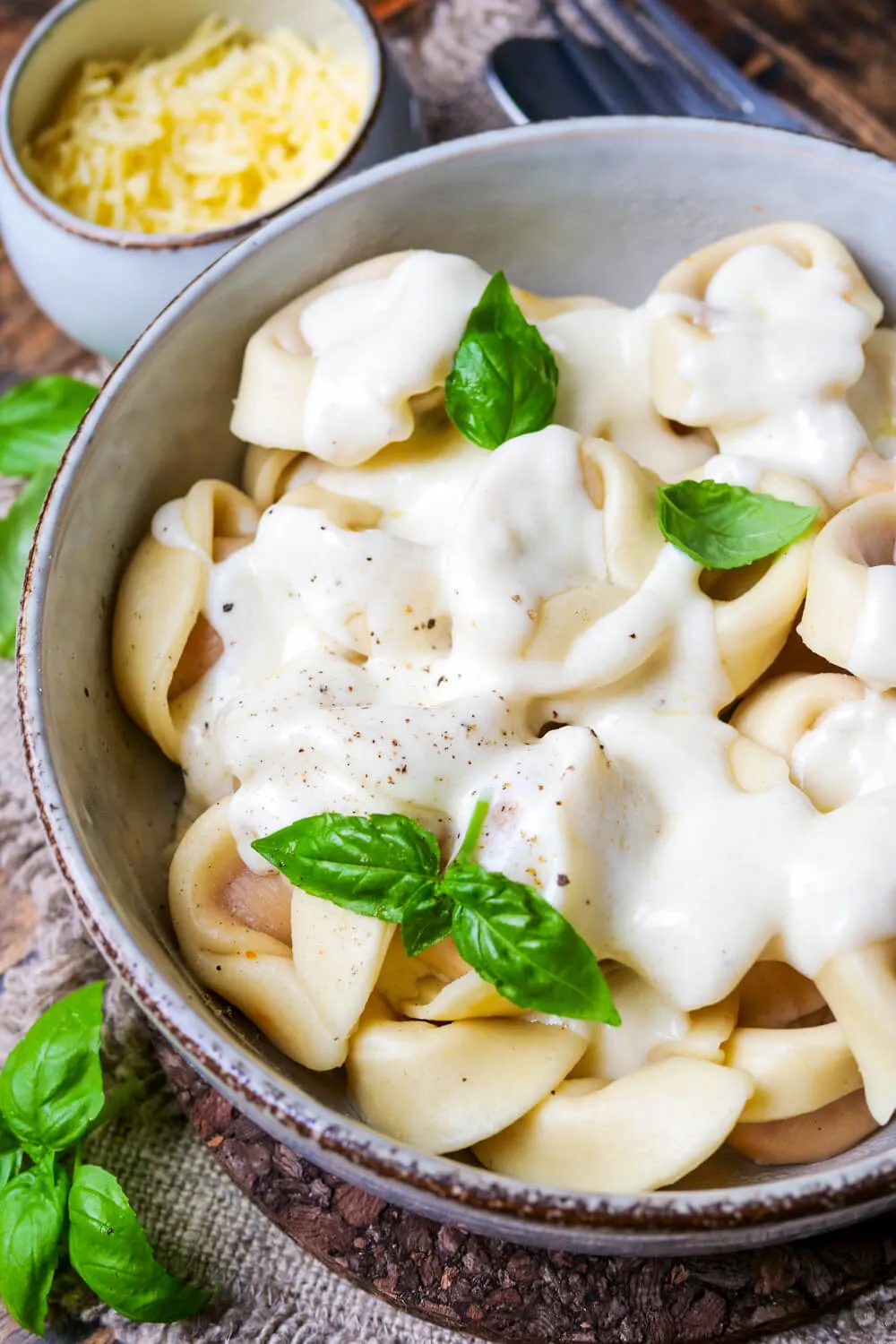 Ein Teller mit Tortellini bedeckt von einer reichhaltigen, schnellen Käsesoße, die ideal für ein einfaches Grundrezept ist.