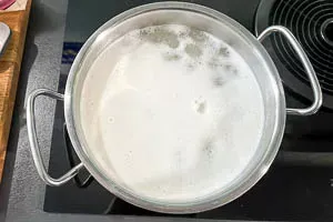 Ein Topf mit Reis, Wasser und Salz wird auf dem Herd zum Kochen gebracht