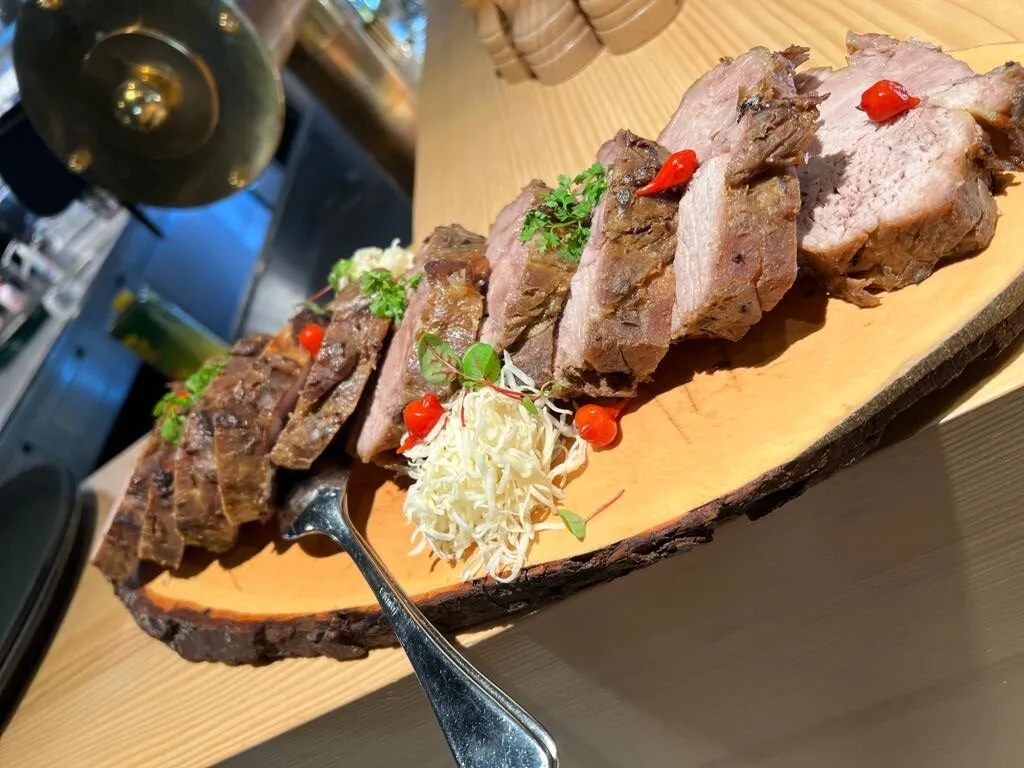 Ein traditioneller Schweinsbraten mit goldbrauner Kruste, angerichtet mit Kartoffeln und Sauce, typisch für ein herzhaftes Sonntagsessen in Deutschland.