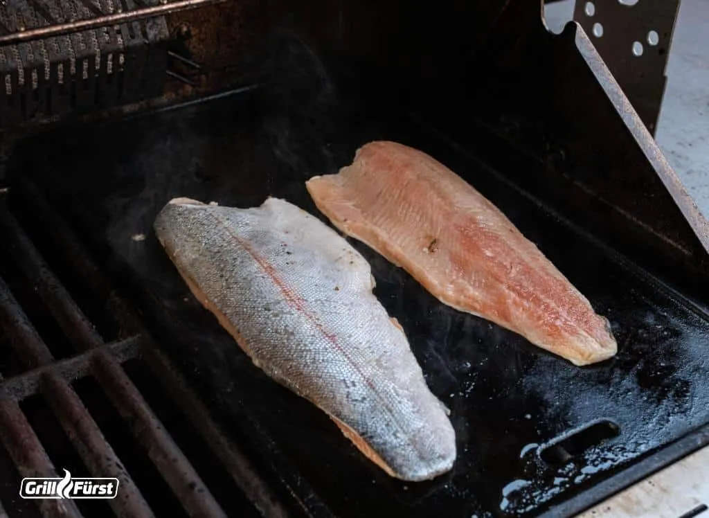 Ein zartes Fischfilet wird auf einer gusseisernen Grillplatte zubereitet, um eine gleichmäßige Bräunung zu erzielen.