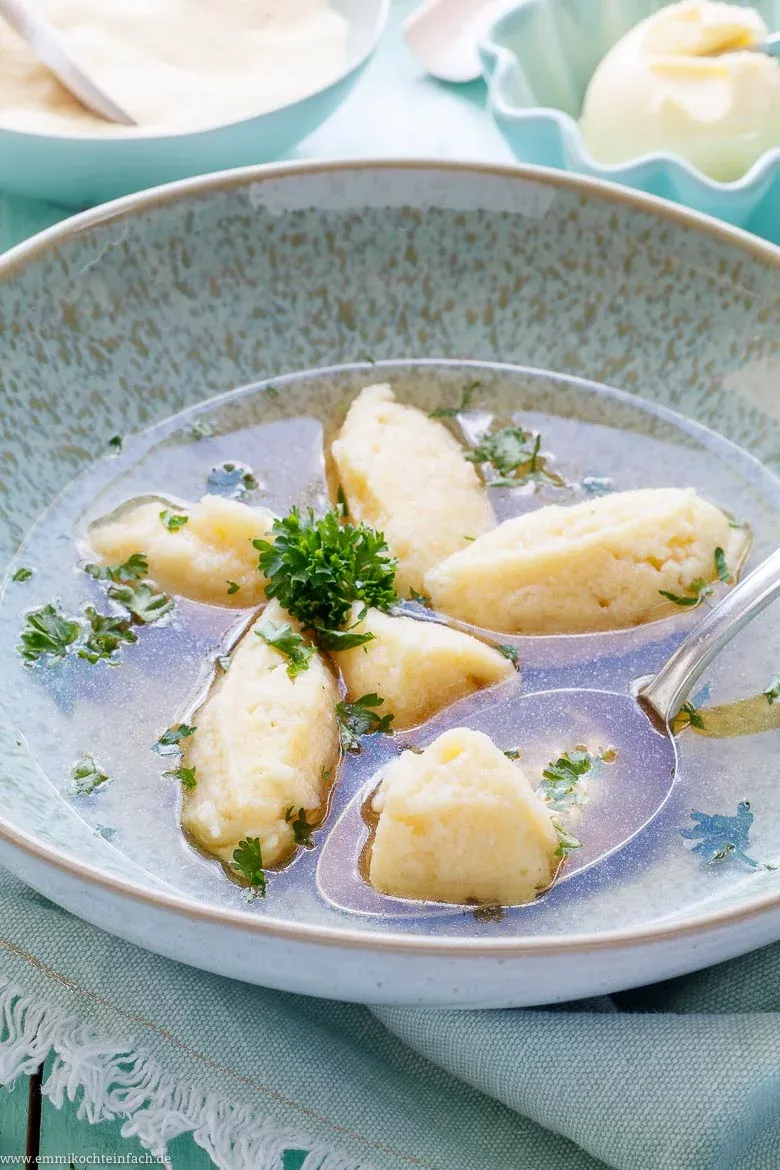Eine appetitliche Grießklößchensuppe mit goldener Brühe und frischen Kräutern in einer weißen Schale.
