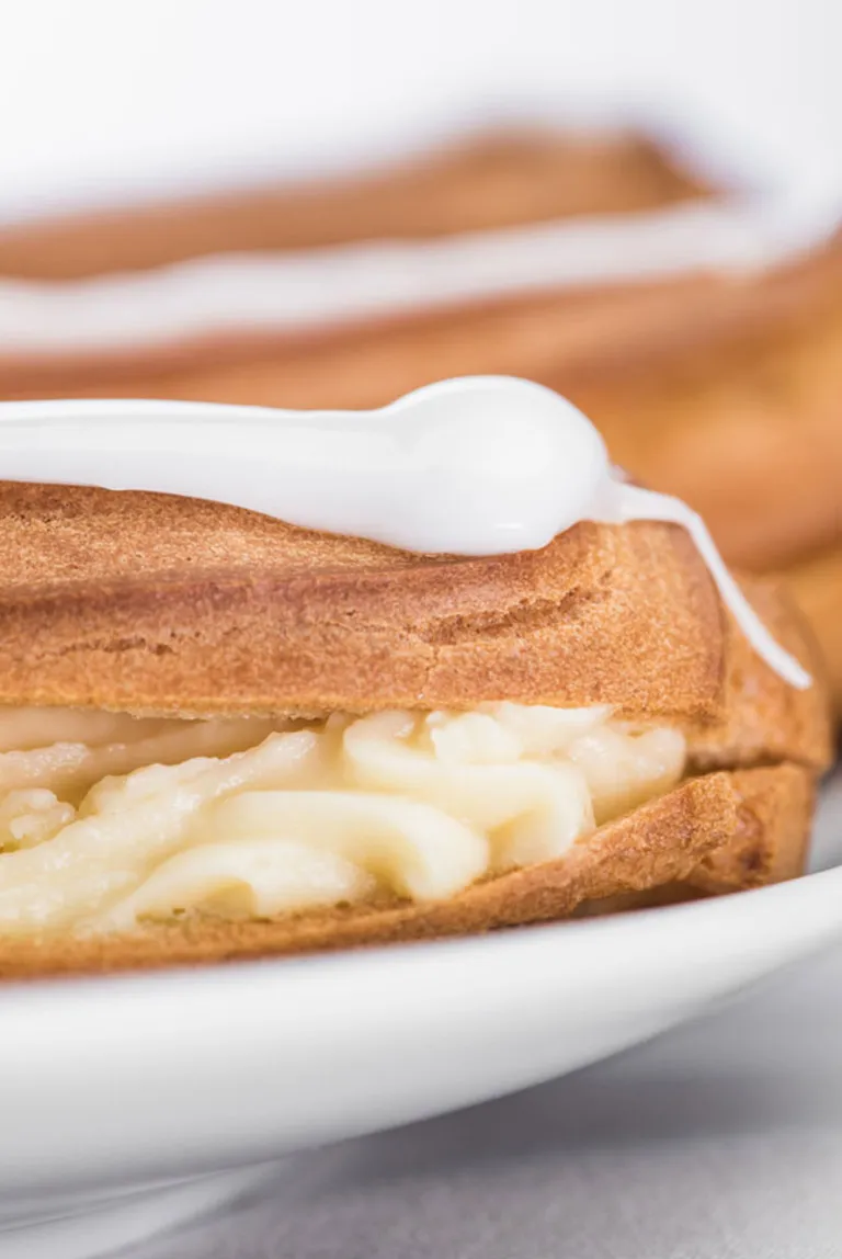 Eine Auswahl an frischen Eclairs mit Vanillefüllung, präsentiert in einer deutschen Konditorei