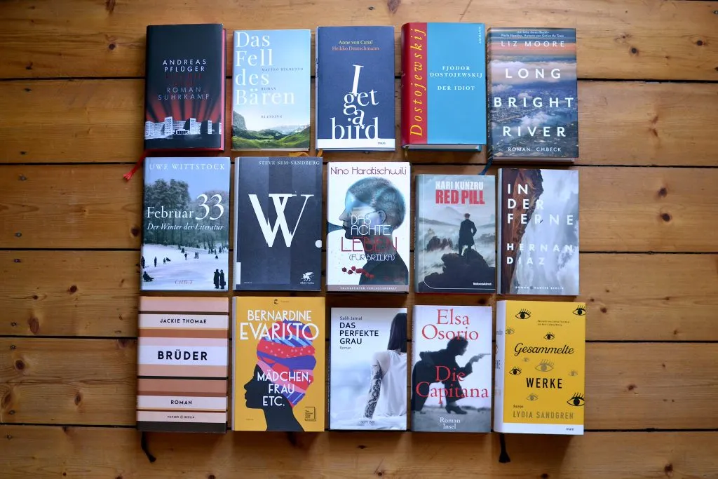 Eine Auswahl der besten Bücher 2021 auf einem Holztisch, darunter Romane und Sachbücher, die zum Lesen und Entdecken deutscher und internationaler Literatur einladen.