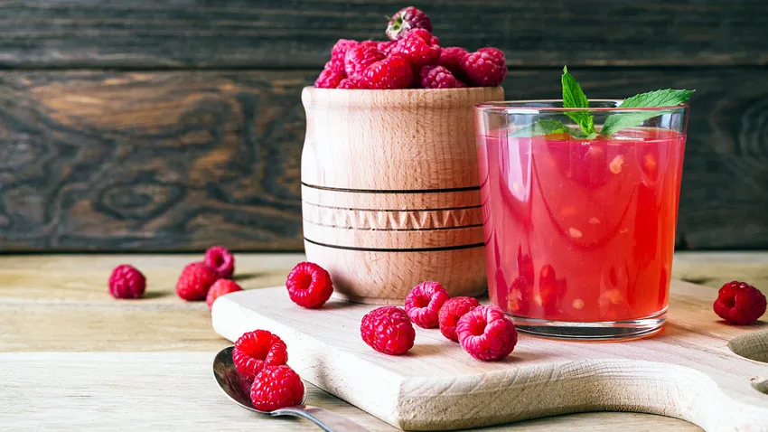 Eine Auswahl traditioneller russischer Getränke, darunter Kwas und Mors, kunstvoll auf einem Holztisch präsentiert.