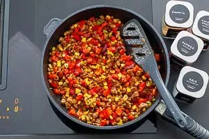 Eine bunte Mischung aus angebratenem Hackfleisch, Mais, Kidneybohnen, Paprika und Gewürzen in einer Pfanne, die köstliche Füllung für Tacos.