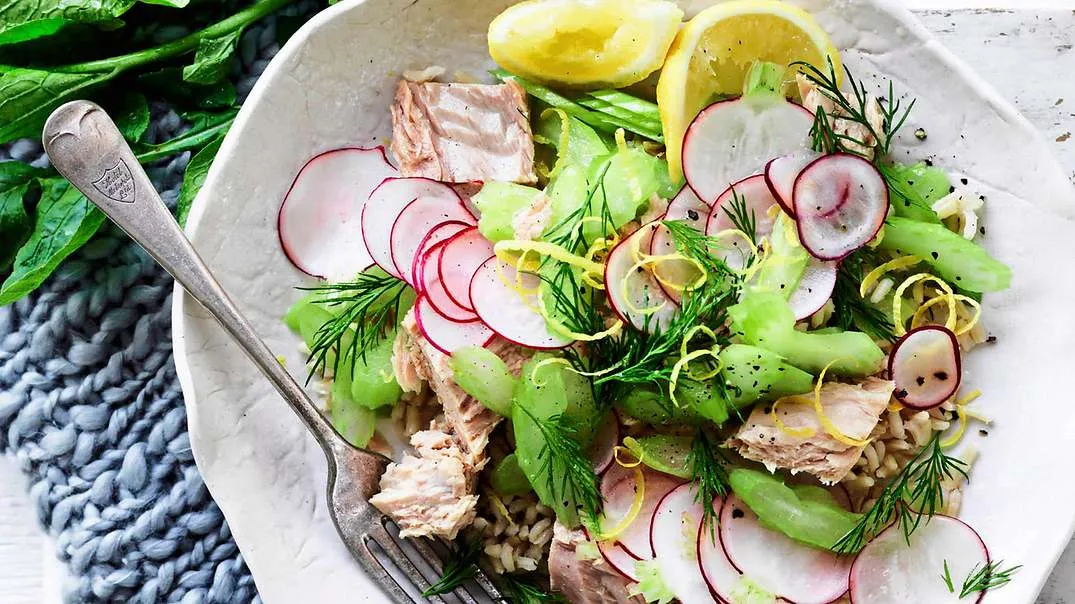 Eine bunte Thunfisch-Reis-Bowl, reichhaltig belegt mit frischen Zutaten wie Gurke, Avocado und Thunfisch, ideal für eine Mittagspause.