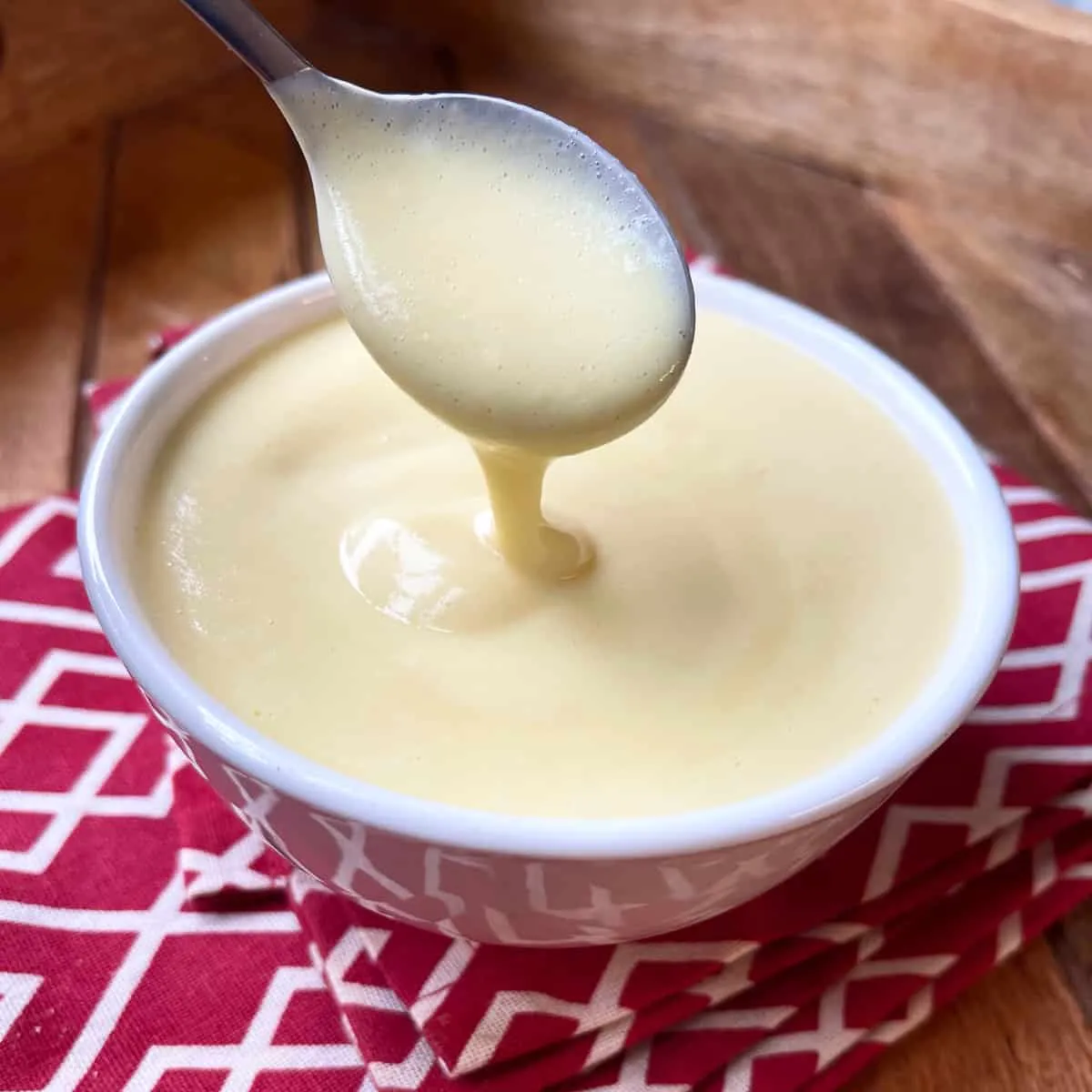 Eine cremige, helle Vanillesauce in einem Schälchen, perfekt als Beilage zu deutschem Apfelkuchen oder anderen Desserts.