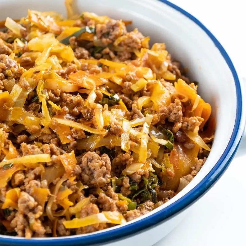 Eine dampfende Pfanne mit Hackfleisch, Lauch und Karotten, ein herzhaftes Gericht.