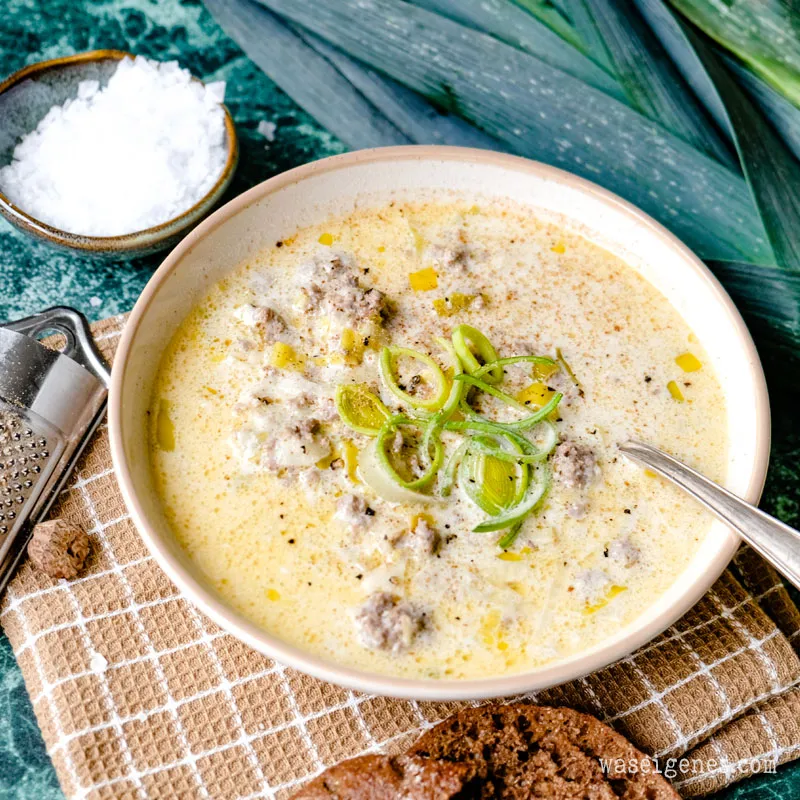Eine dampfende Portion Hackfleisch-Lauch-Suppe in einer rustikalen Schüssel, serviert mit einem Stück knusprigem Brot.