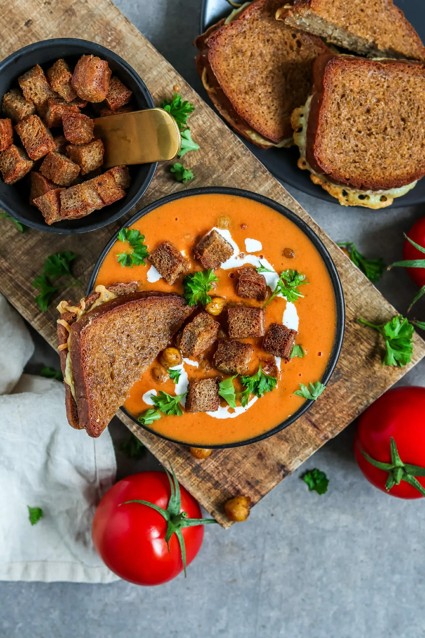 Eine dampfende Schüssel cremige vegane Tomatensuppe, garniert mit knusprigen Kichererbsen und frischer Petersilie, bereit zum Genuss.