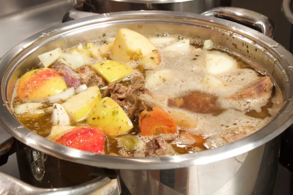 Eine dunkelbraune, reichhaltige Gänsesauce, die langsam in einem Topf köchelt.