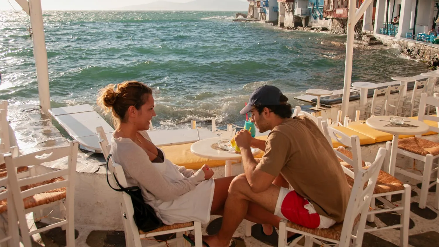 Eine entspannte Szene in einer Strandbar auf Mykonos, Griechenland, mit Blick auf das glitzernde Meer