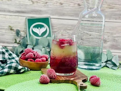 Eine erfrischende Himbeerlimonade mit frischen Himbeeren und Minze, serviert in einem Glas