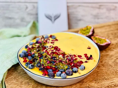 Eine exotische Kokos-Mango-Smoothie-Bowl mit Kokosraspeln und frischen Früchten