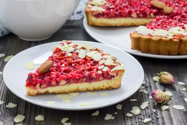 Eine exquisite Frangipane-Tarte mit Aprikosen, elegant präsentiert und mit Puderzucker bestreut, als raffinierte Geburtstagskuchen-Alternative.