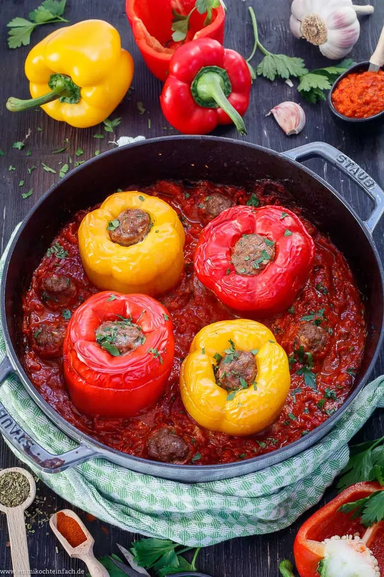 Eine fertig zubereitete gefüllte Paprika mit würziger Hackfleischfüllung und frischer Petersilie garniert, in einer tiefen Auflaufform mit mediterraner Tomatensoße, bereit zum Servieren.