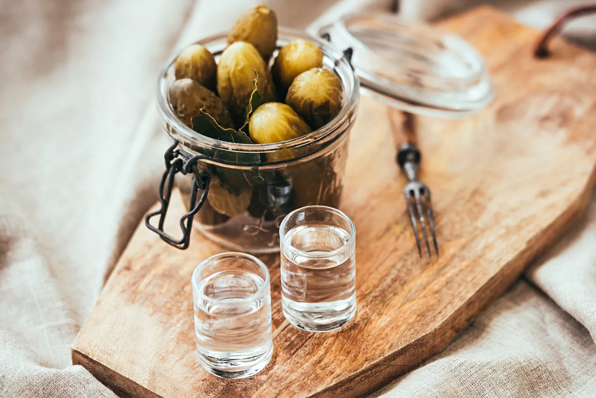 Eine Flasche Wodka und kleine Gläser, bereit für traditionelle russische Trinkrituale, oft begleitet von herzhaften 'Zakuski'.