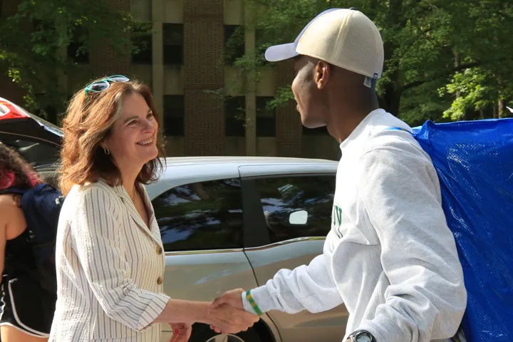 Eine führende Persönlichkeit des öffentlichen Lebens (links) begrüßt zukünftige Talente und ihre Familien während eines Aufbruchsereignisses.