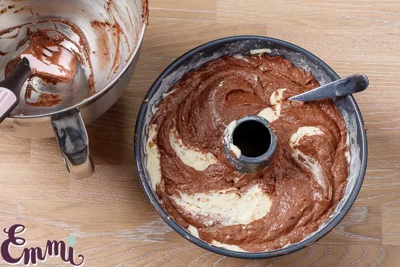 Eine Gabel wird spiralförmig durch den hellen und dunklen Teig gezogen, um das gewünschte Marmormuster im Kuchen zu erzeugen