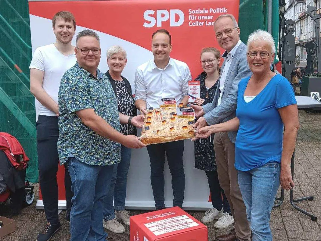 Eine Gruppe von Menschen genießt Geburtstagskuchen an einem Stand im Freien
