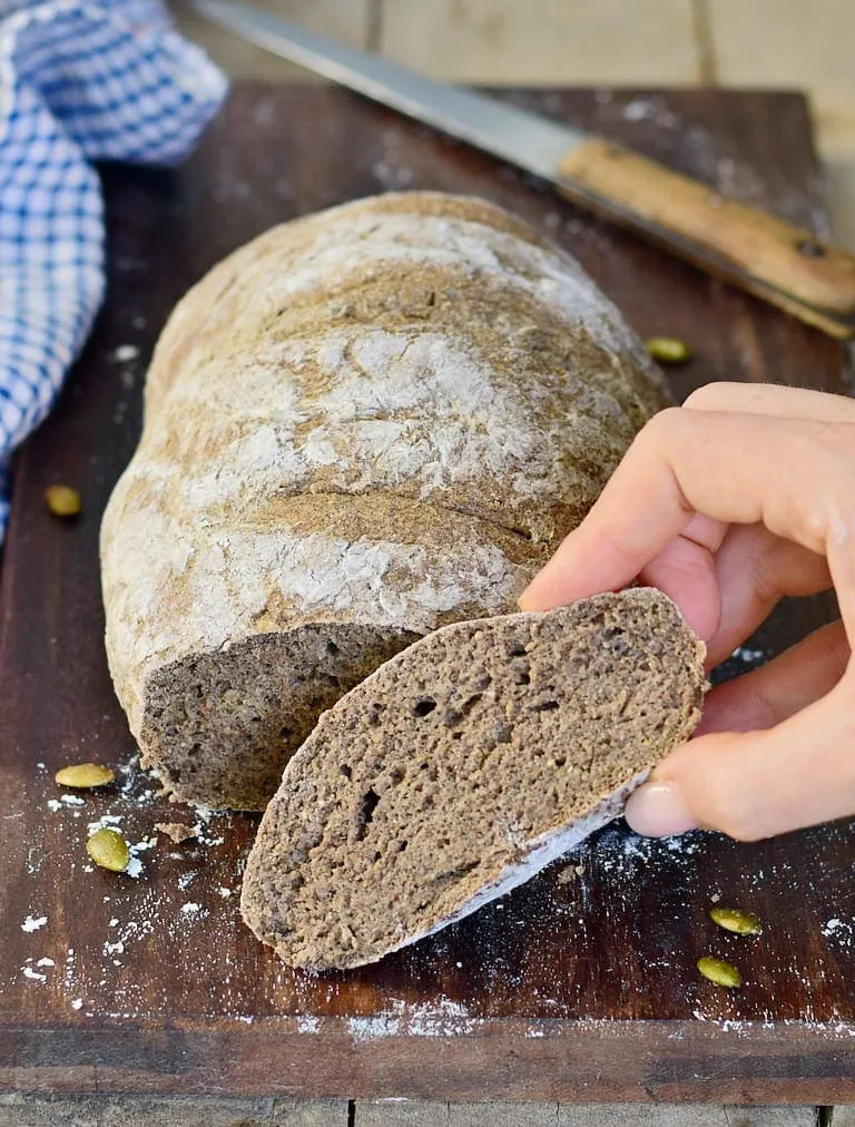 Eine Hand hält eine fluffige Scheibe selbstgemachtes glutenfreies veganes Brot, das die weiche Textur zeigt