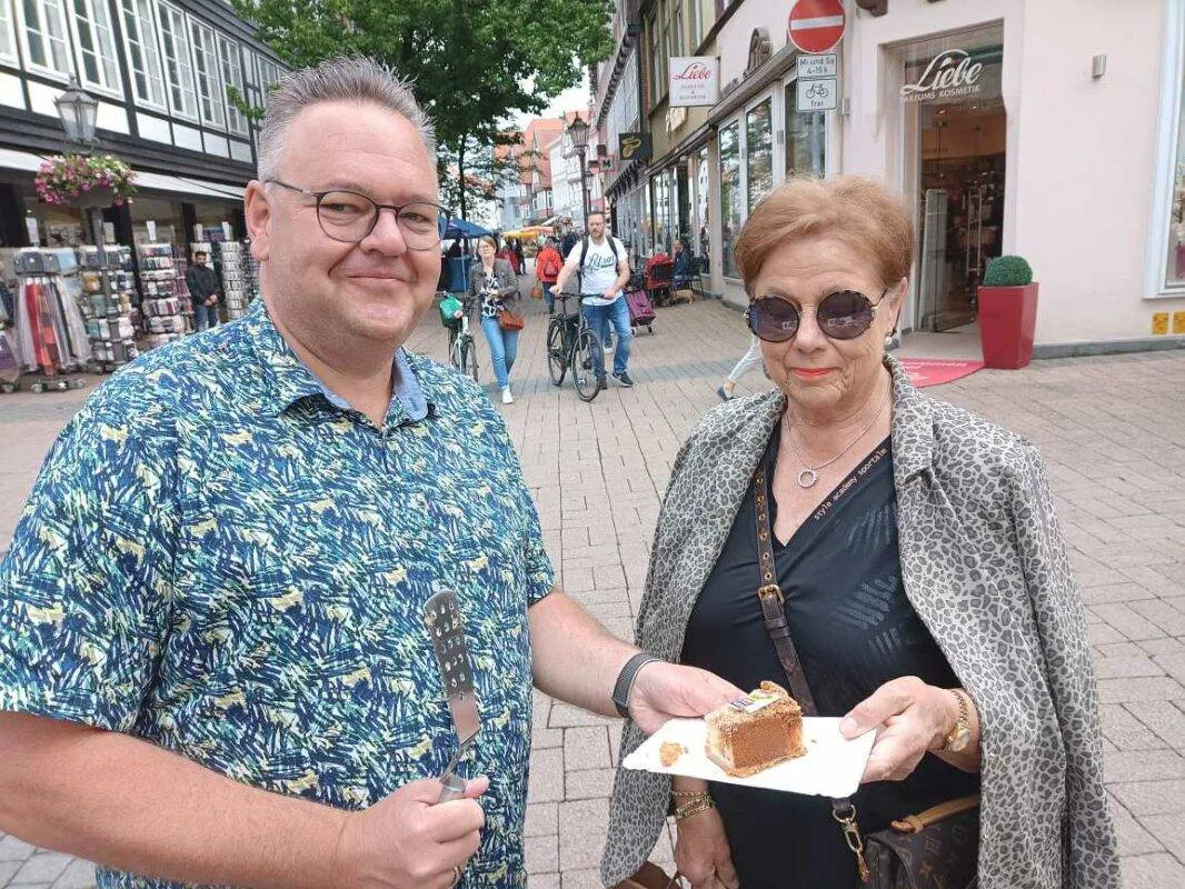 Eine Hand reicht ein Stück Geburtstagskuchen von einem Tablett an eine Person