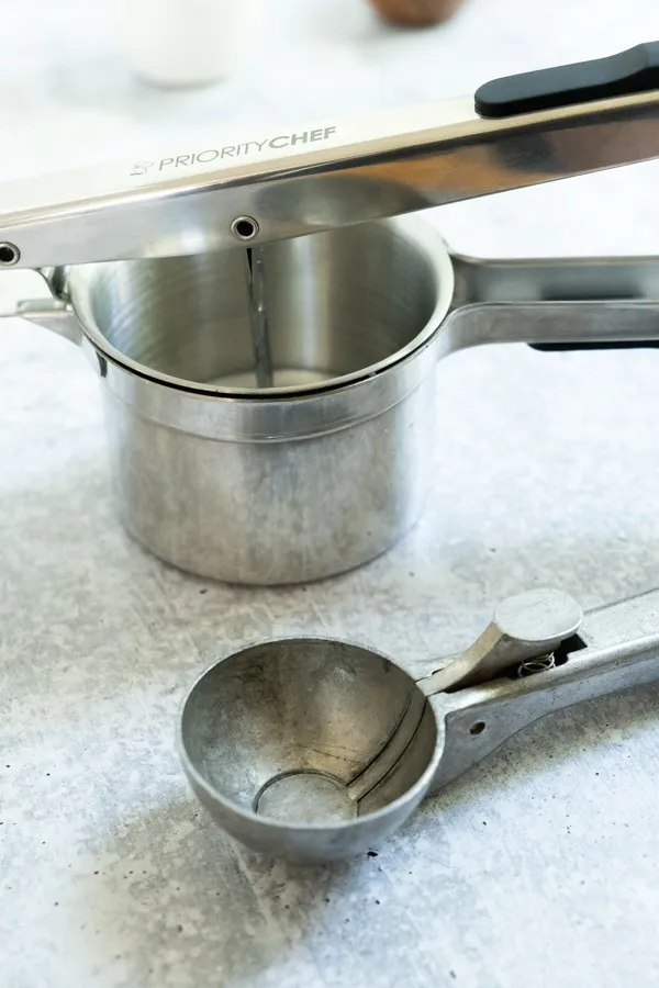 Eine Kartoffelpresse und ein Eiskugelportionierer im Gefrierschrank vor der Verwendung