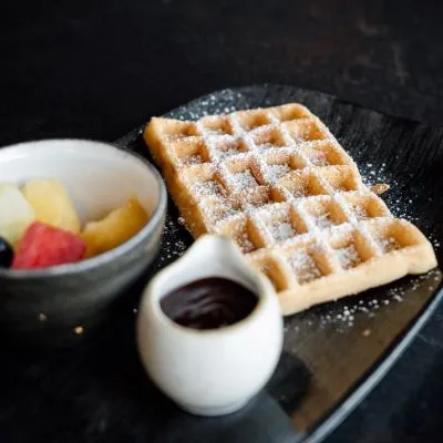 Eine köstliche glutenfreie Waffel mit frischen Früchten und Schokoladensauce in einem gemütlichen Café, das glutenfreie Optionen anbietet