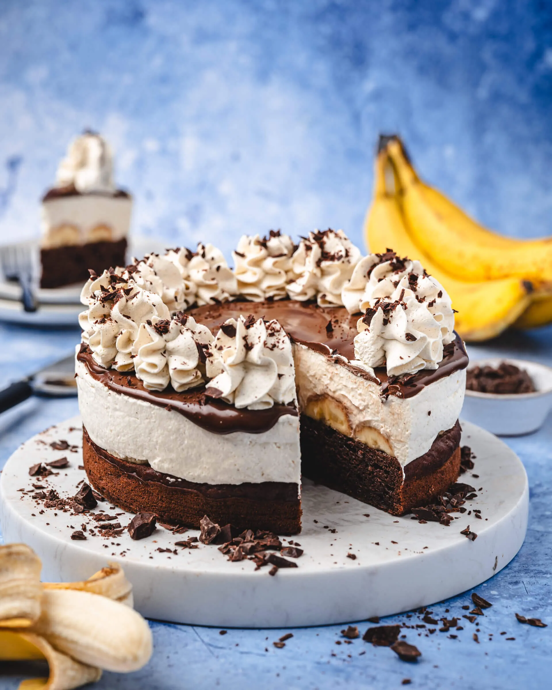 Eine köstliche Schoko-Bananen-Sahne-Torte, kunstvoll dekoriert und bereit zum Servieren auf einer festlichen Kaffeetafel.