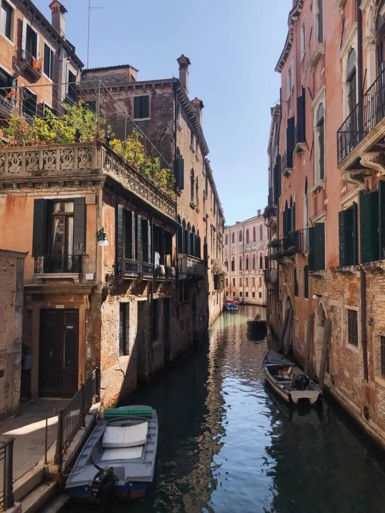 Eine malerische Szene in Venedig: Ein Kanal schlängelt sich durch die Stadt, gesäumt von historischen Gebäuden. Das ruhige Wasser spiegelt die Architektur wider und schafft eine romantische Atmosphäre.