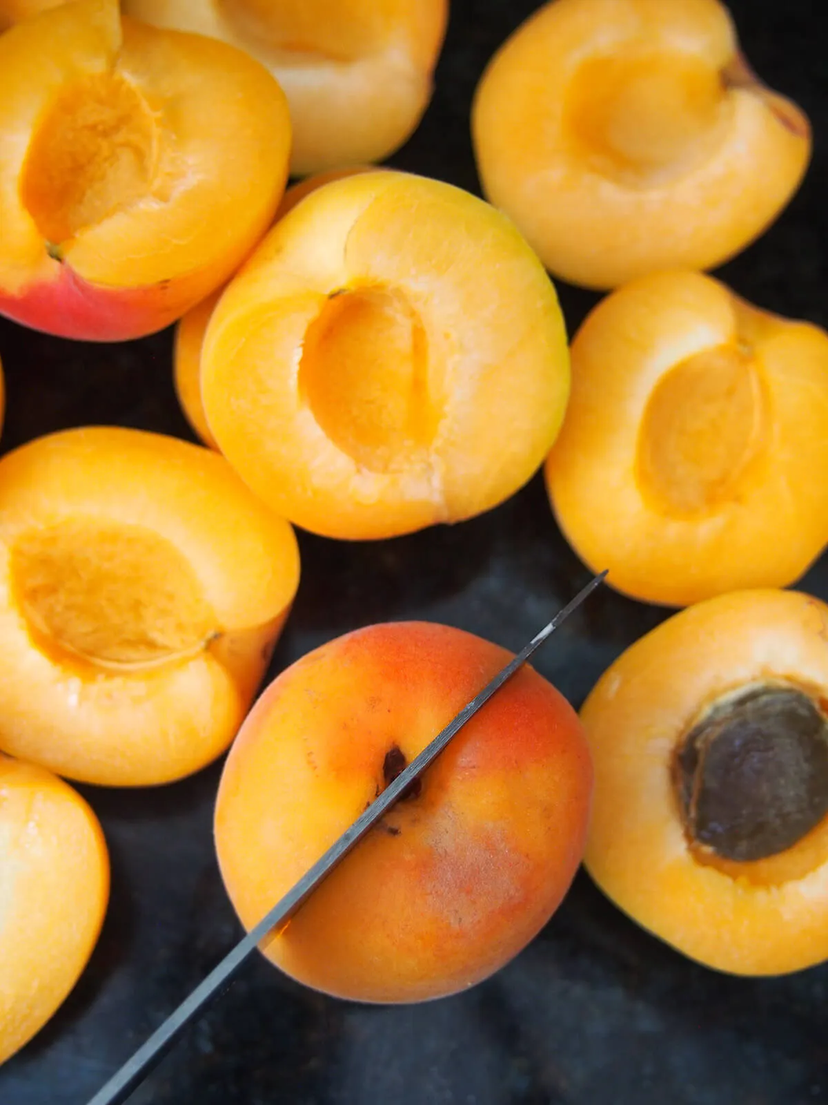 Eine Nahaufnahme von halbierten Aprikosen, deren Kerne entfernt werden