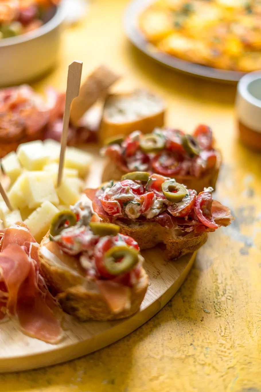 Eine Nahaufnahme von spanischen Tomatenbroten, garniert mit Serrano-Schinken, Ziegenkäse und Oliven, ein klassisches Element der spanischen Vorspeisen.