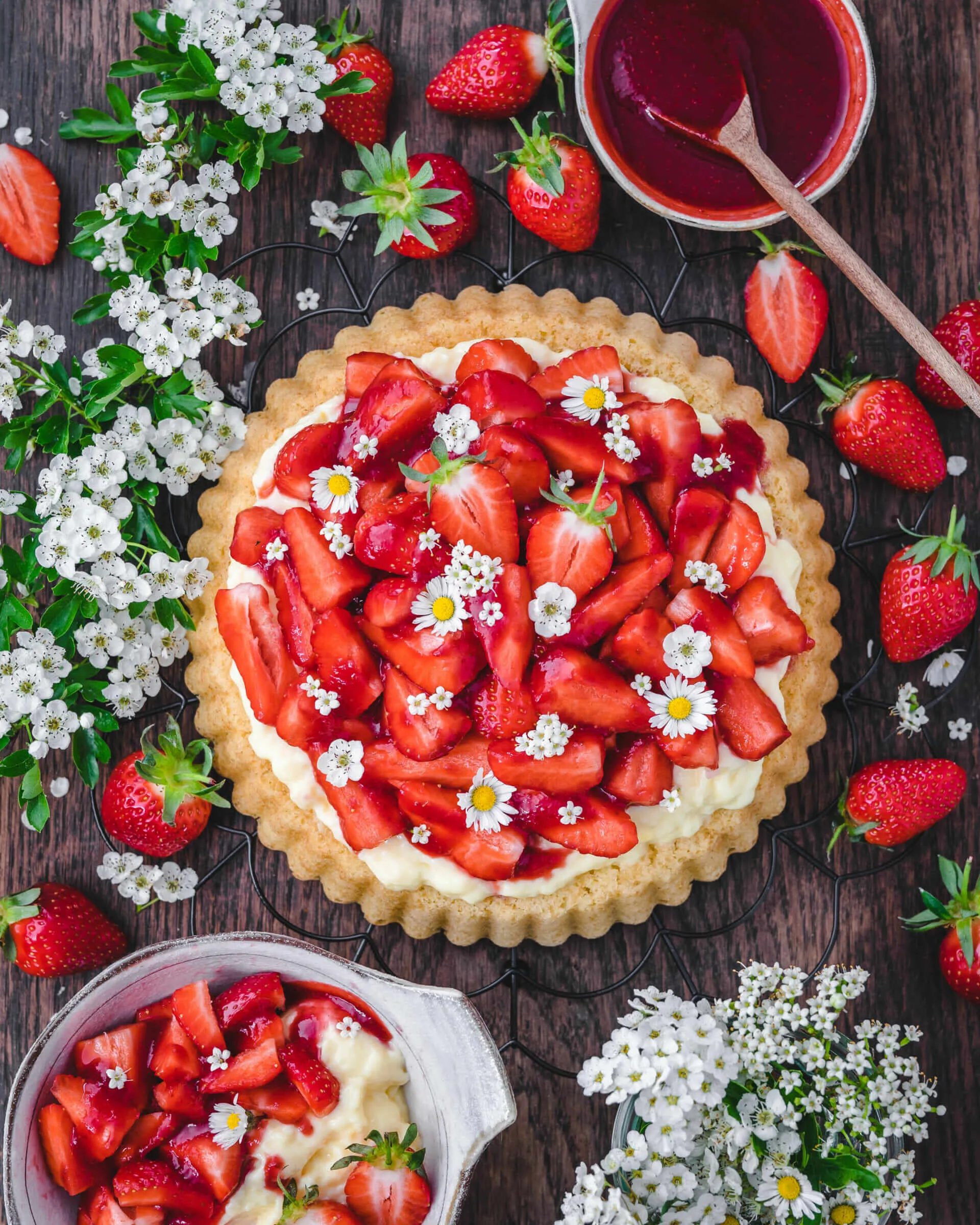 Eine Nahaufnahme zeigt ein Stück vegane Erdbeer Pudding Sahne Torte mit luftigem Boden, cremiger Füllung und frischen Erdbeeren, angeschnitten auf einem Teller.