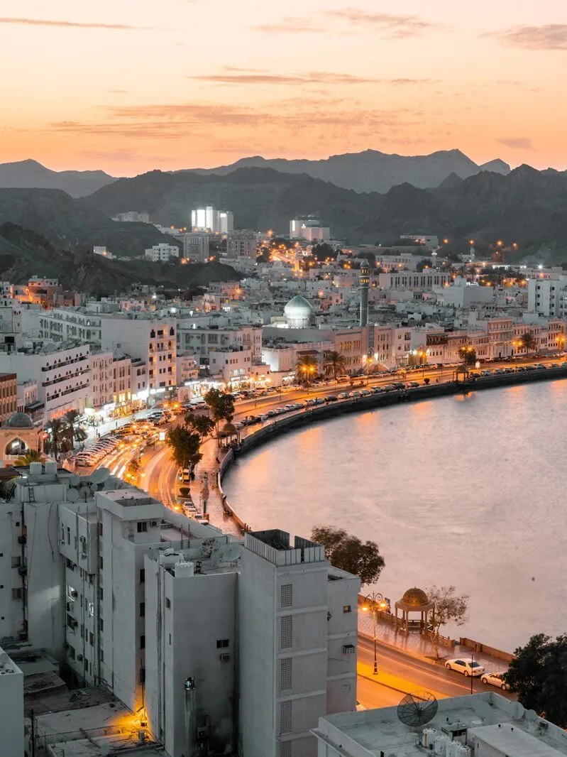 Eine Oase in der Wüste des Oman mit Dattelpalmen und einem traditionellen Lehmhaus