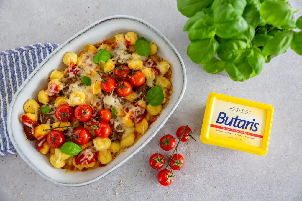 Eine ofenfeste Form gefüllt mit Ofen-Gnocchi und Hackbällchen, die mit frischem Basilikum garniert sind und zum Servieren bereitstehen.